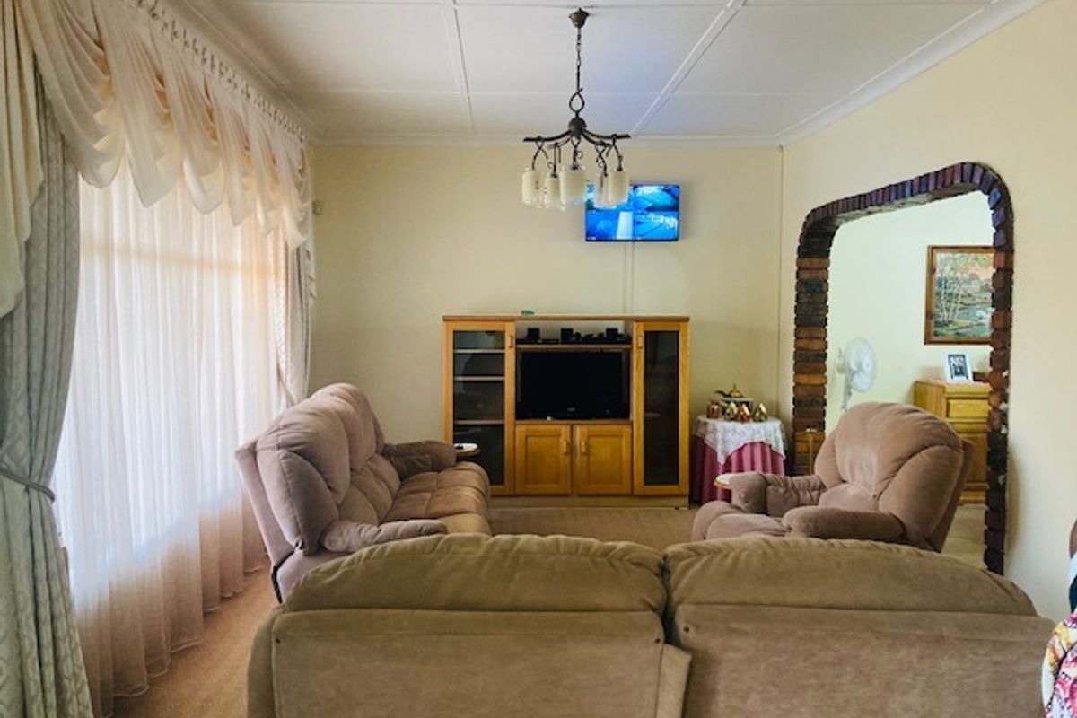 A traditional living room featuring a brick archway, tiled ceiling, and large window with draped curtains, providing a comfortable and classic living space.