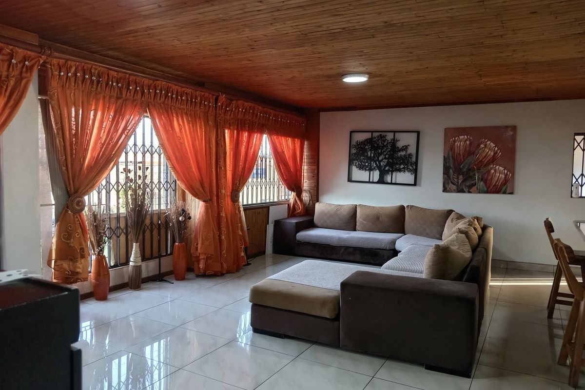 Spacious living area featuring polished tile flooring and a warm timber-clad ceiling, providing a comfortable and inviting atmosphere.