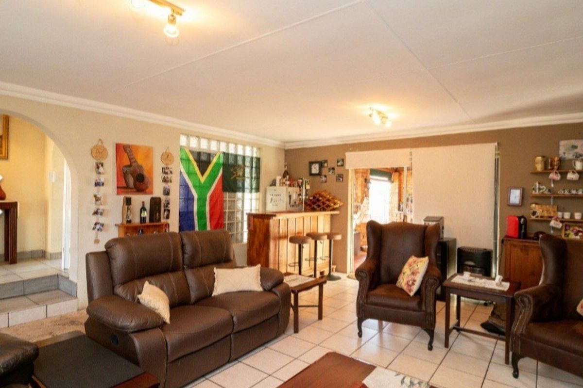 Spacious living area featuring tiled flooring, a built-in bar with glass block accents, and an arched entryway leading to adjacent rooms.