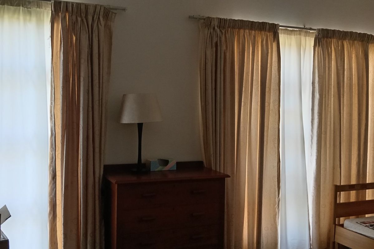 A bedroom featuring dual windows with curtains, providing natural light and a neutral interior space.