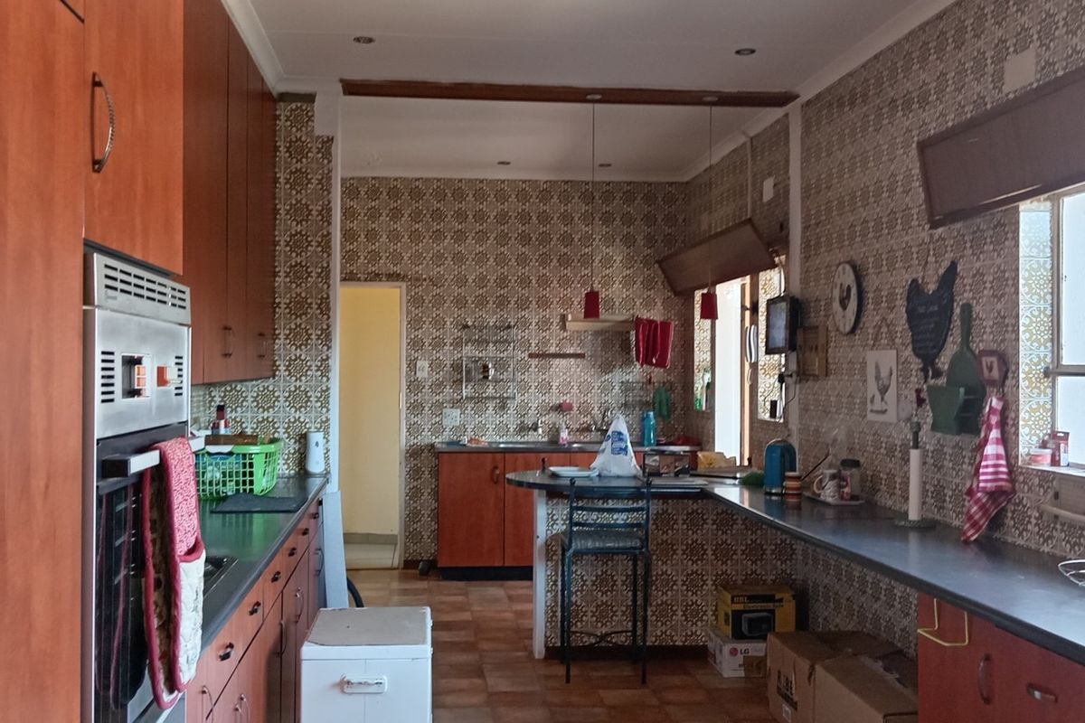 Spacious kitchen featuring extensive wooden cabinetry, integrated oven, and a breakfast bar, offering significant potential for a modern renovation.