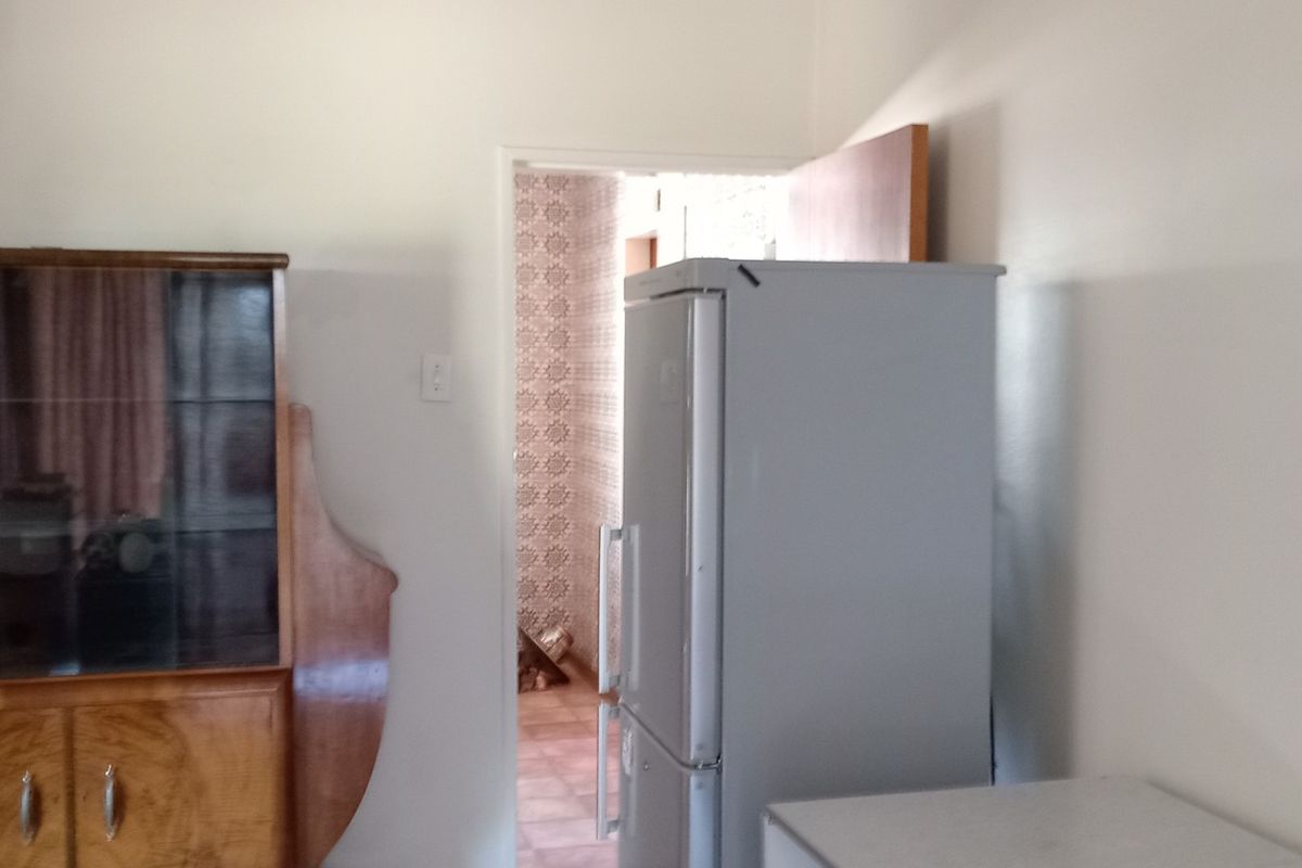 A view of a room leading into a secondary space with patterned wall tiles and tiled flooring.