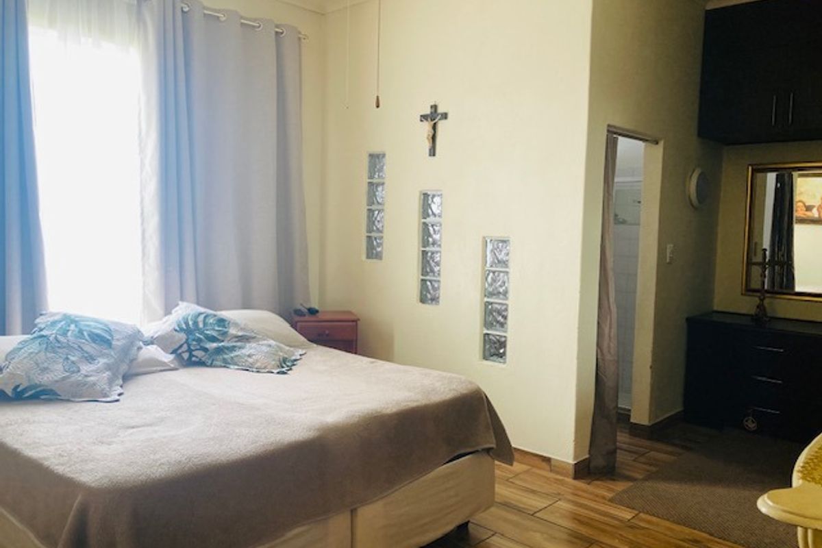 A bedroom featuring tiled flooring, glass block wall accents, and an en-suite bathroom entrance.