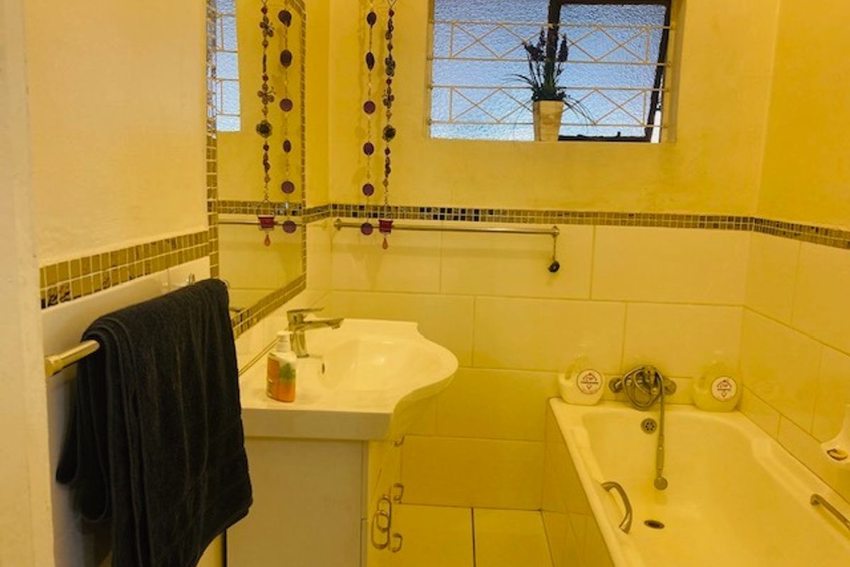A functional bathroom featuring a built-in bathtub, pedestal sink, and mosaic tile accents, providing a practical space for daily use.
