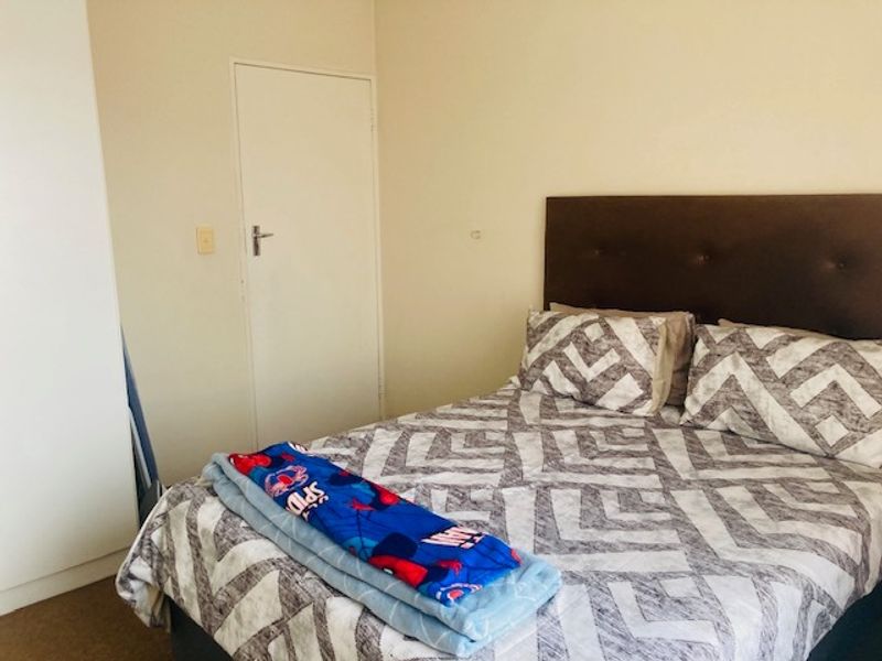 A standard bedroom featuring neutral walls, carpeted flooring, and a built-in wardrobe.