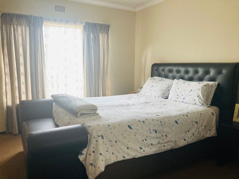 A standard bedroom featuring neutral walls and a ceiling ventilation unit, providing a functional space for rest.