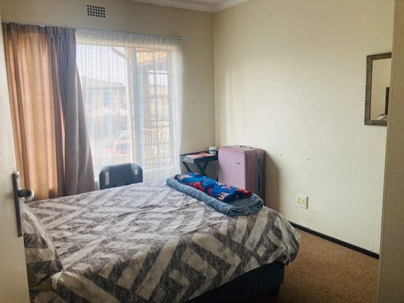 A standard bedroom featuring carpeted flooring, neutral wall finishes, and a sliding door providing access to an outdoor area.