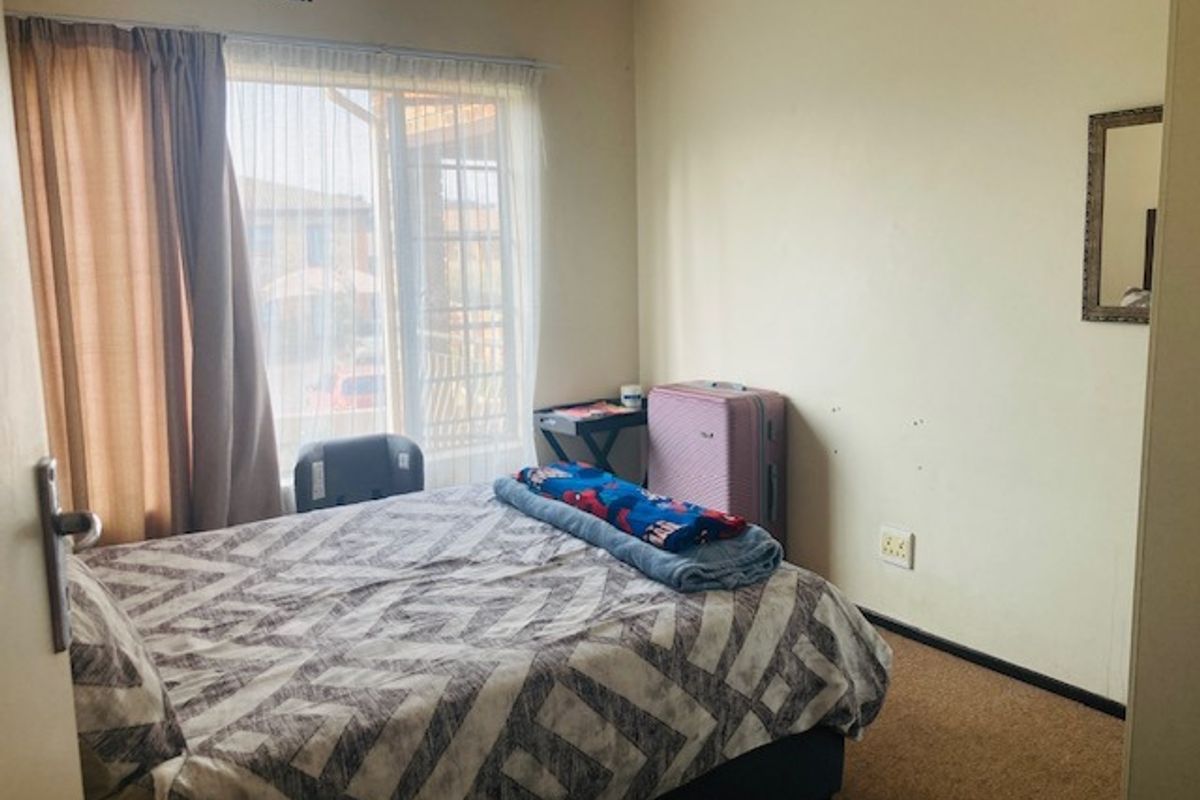 A standard bedroom featuring carpeted flooring, neutral wall finishes, and a sliding door providing access to an outdoor area.
