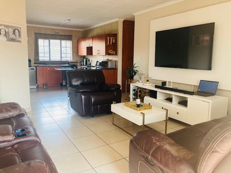 Open-plan living area featuring tiled flooring and a functional kitchen with built-in cabinetry, creating a combined space for relaxation and dining.