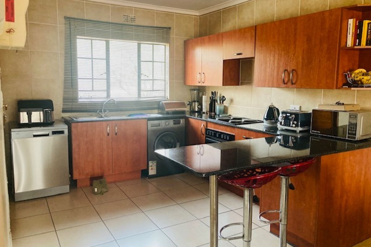 Functional kitchen featuring wood-finish cabinetry, granite countertops, tiled backsplash, and a breakfast bar, providing a practical layout for daily meal preparation.