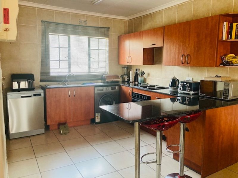 Functional kitchen featuring wood-finish cabinetry, granite countertops, tiled backsplash, and a breakfast bar, providing a practical layout for daily meal preparation.