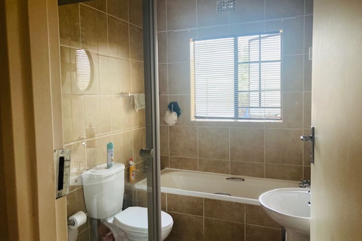 A functional bathroom featuring a bathtub, pedestal basin, toilet, and a separate shower enclosure with tiled walls and flooring.