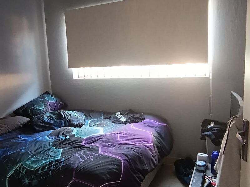 A compact bedroom featuring tiled flooring, cove cornicing, and a fitted roller blind over the window.