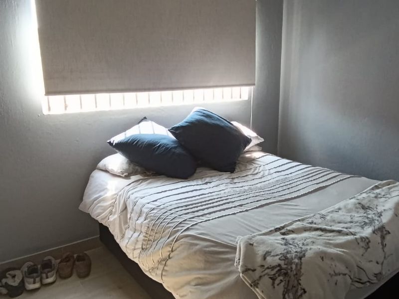 A bedroom featuring grey painted walls, tiled flooring, and a fitted roller blind with decorative ceiling cornicing.