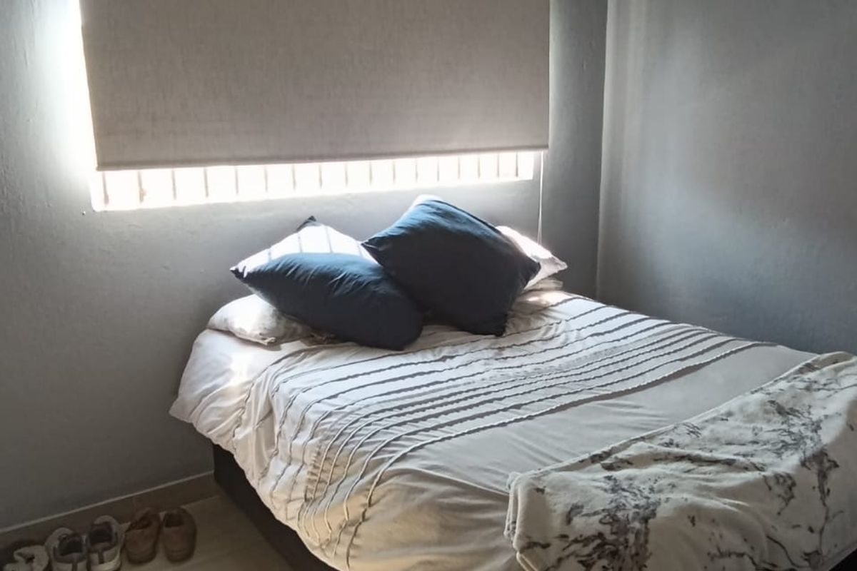 A bedroom featuring grey painted walls, tiled flooring, and a fitted roller blind with decorative ceiling cornicing.