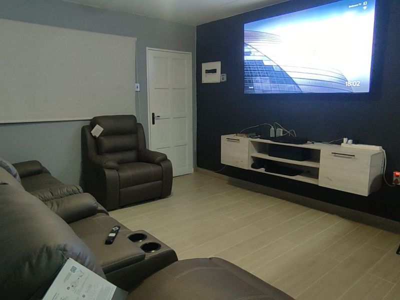 A living room featuring tiled flooring, a wall-mounted media console, and a roller blind, providing a functional and modern living space.