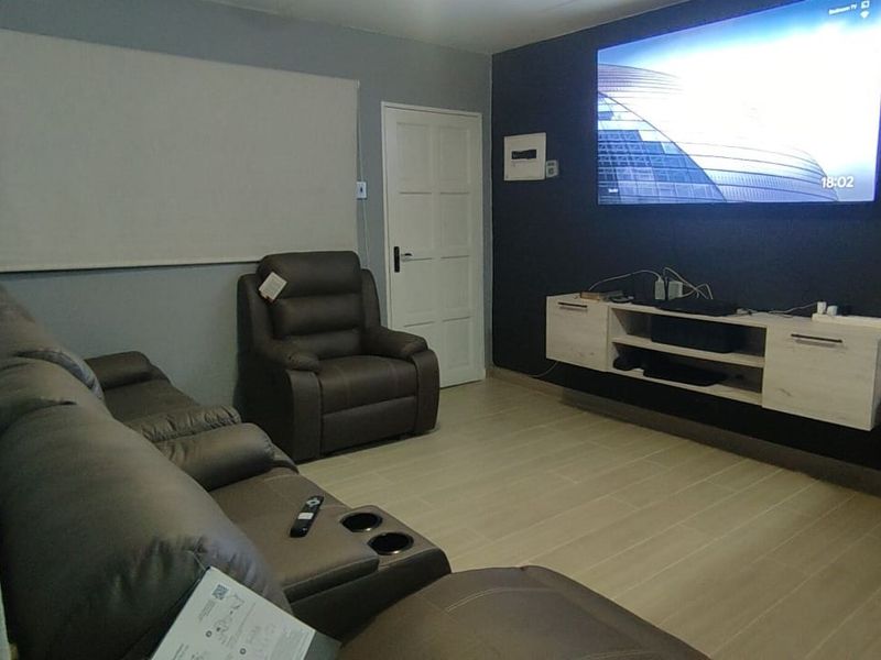 A comfortable living room featuring tiled flooring, a wall-mounted media console, and a neutral color palette with a dark accent wall.