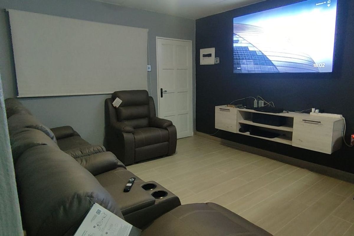 A comfortable living room featuring tiled flooring, a wall-mounted media console, and a neutral color palette with a dark accent wall.