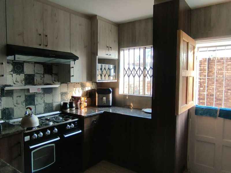 A functional kitchen featuring built-in cabinetry, granite countertops, a gas stove with extractor fan, and a stable-style door leading to the exterior.
