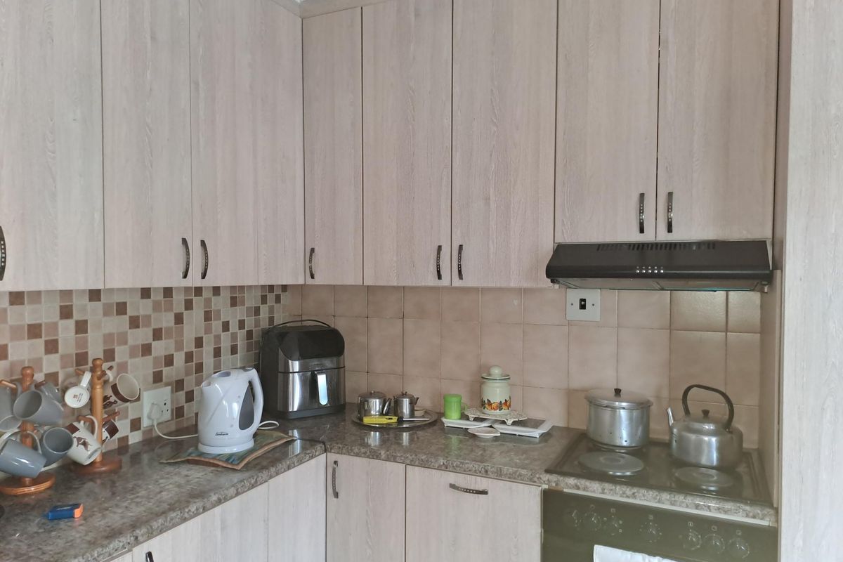 Functional kitchen featuring light wood-grain cabinetry, granite-look laminate countertops, a mosaic tile backsplash, and integrated cooking appliances.