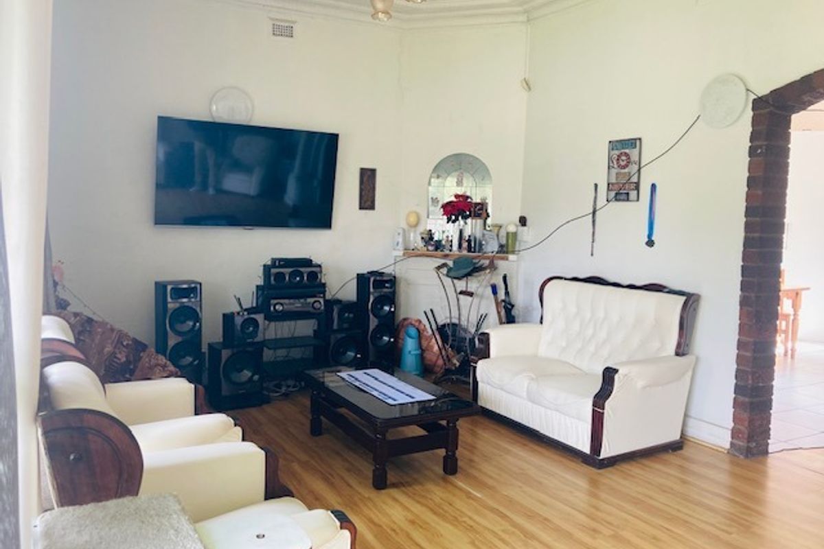 A living room featuring laminate flooring, a decorative ceiling rose, and a brick archway leading to an adjacent space.