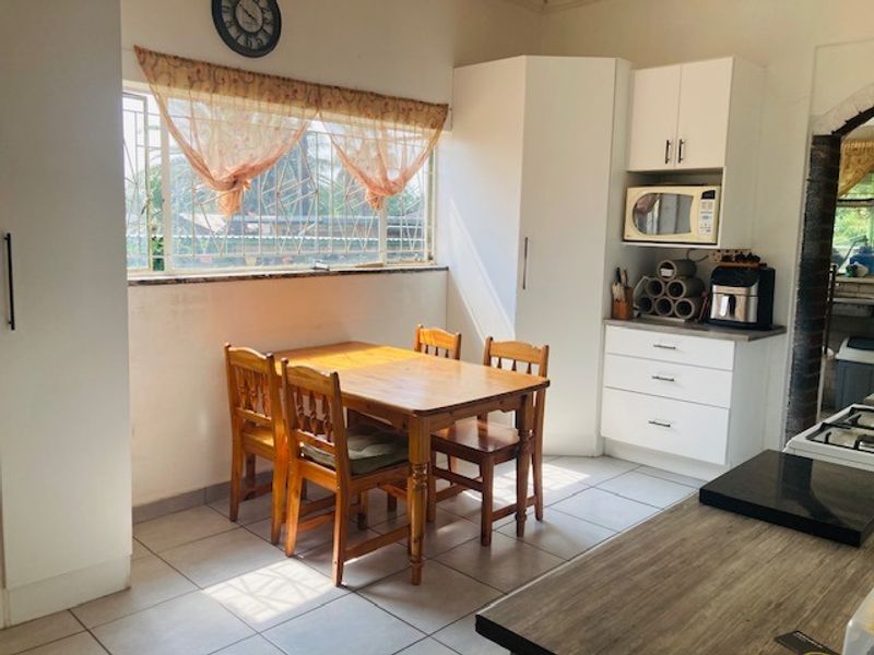 A functional kitchen area featuring tiled flooring, built-in white cabinetry, and a dedicated dining space with natural light from the window.