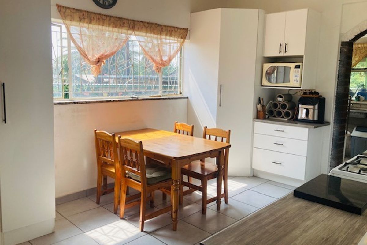 A functional kitchen area featuring tiled flooring, built-in white cabinetry, and a dedicated dining space with natural light from the window.