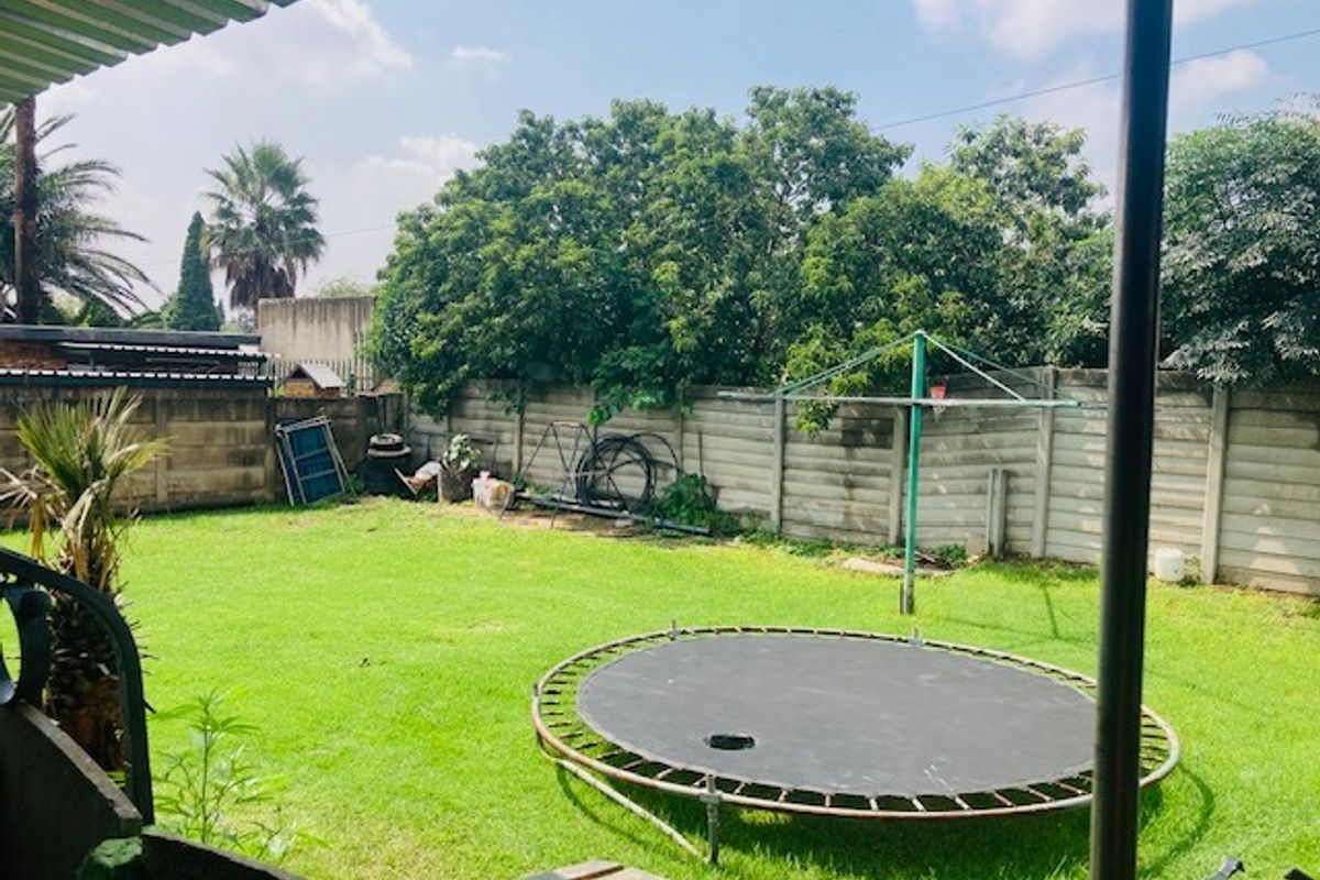 A spacious rear garden featuring a well-maintained lawn, enclosed by a precast concrete boundary wall, providing a private outdoor area.