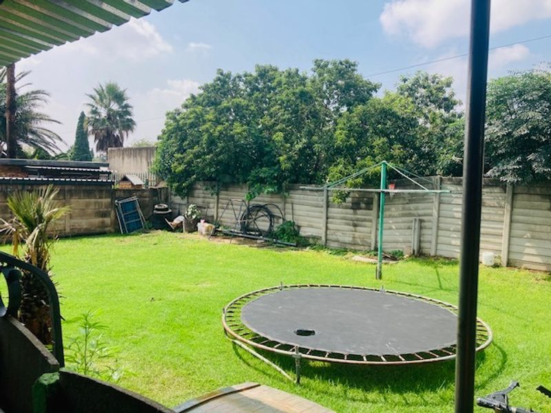 A spacious rear garden featuring a well-maintained lawn, enclosed by a precast concrete boundary wall, providing a private outdoor area.