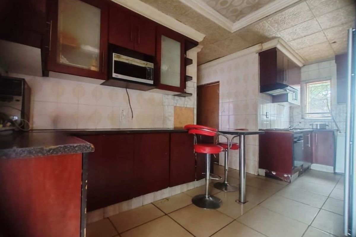 A dated kitchen featuring dark wood cabinetry, tiled flooring, and a drop ceiling, offering significant potential for a modern renovation.