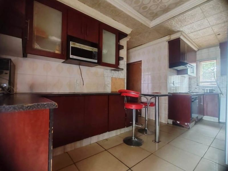 A dated kitchen featuring dark wood cabinetry, tiled flooring, and a drop ceiling, offering significant potential for a modern renovation.