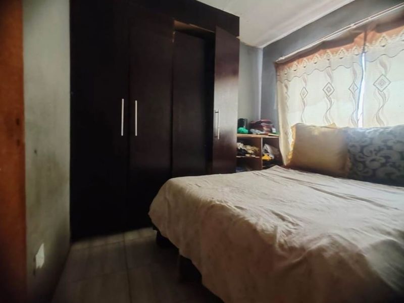 A bedroom featuring a dark built-in wardrobe and tiled flooring, requiring cosmetic updates to improve the overall aesthetic and finish.