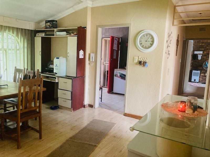A living area featuring laminate flooring, built-in cabinetry, and an archway leading to an adjacent room with a security gate.