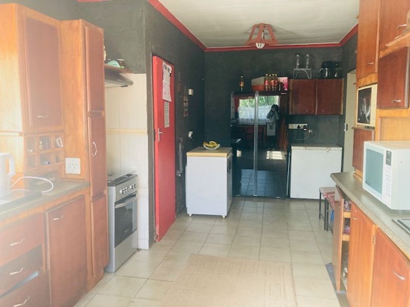 A dated kitchen featuring wooden cabinetry, tiled flooring, and a built-in oven, offering significant potential for a modern renovation.