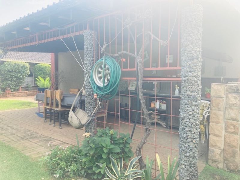 A covered outdoor patio area featuring stone-clad pillars and a built-in braai, providing a functional space for outdoor entertaining and relaxation.