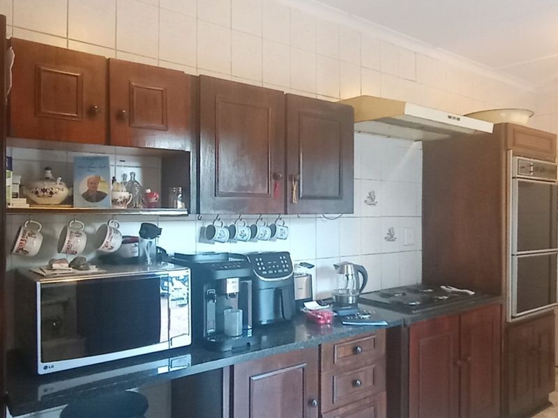 A traditional kitchen featuring dark wood cabinetry, built-in oven, hob, extractor fan, and tiled splashbacks.