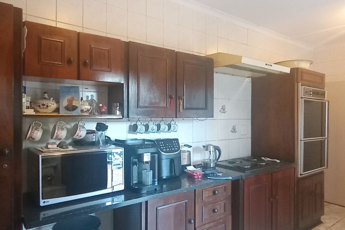 A traditional kitchen featuring dark wood cabinetry, built-in oven, hob, extractor fan, and tiled splashbacks.