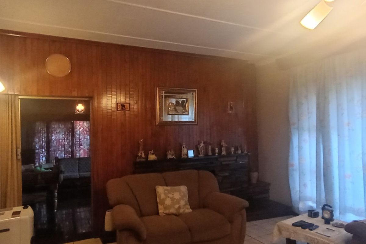 Living room featuring wood paneling, tiled flooring, and a built-in fireplace, offering a traditional aesthetic with potential for modernization.