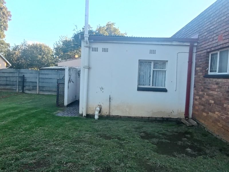 Rear view of the property showing a brick and plastered exterior, precast boundary wall, and a small garden area.