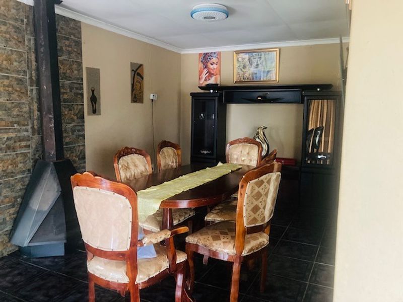 Dining room featuring a stone-clad feature wall with a freestanding fireplace and tiled flooring.