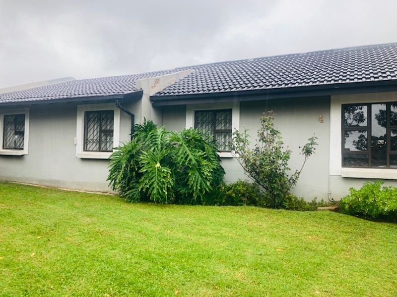Front facade of a single-story residential house featuring a tiled roof, aluminium window frames with security bars, and a well-maintained lawn.