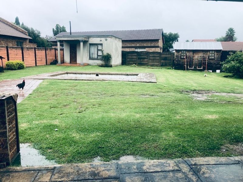 Spacious rear garden featuring a swimming pool, paved patio area, and a detached wooden storage shed enclosed by boundary walls.