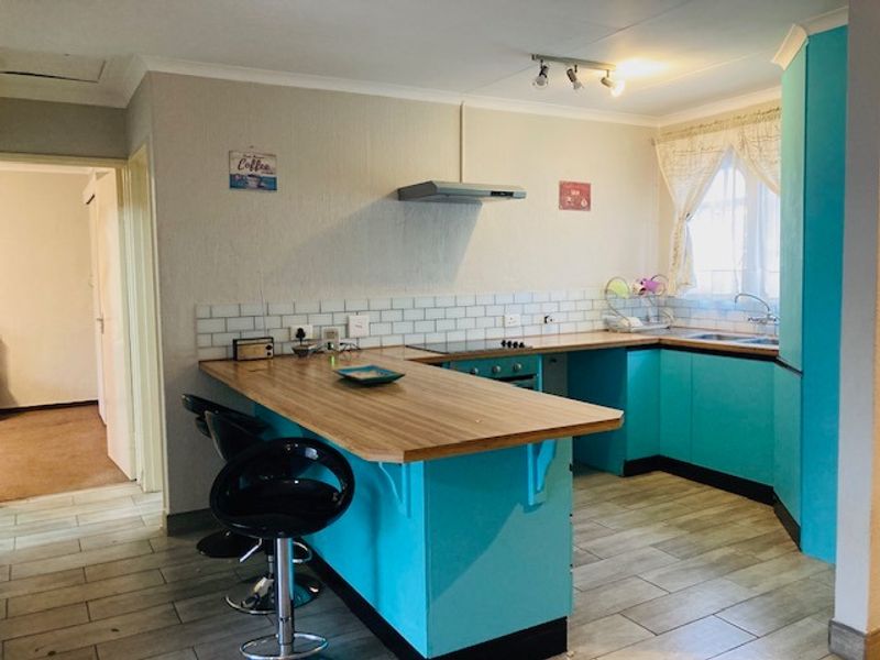 A functional kitchen featuring bright blue cabinetry, a wood-look laminate breakfast bar, subway tile backsplash, and integrated cooking appliances.