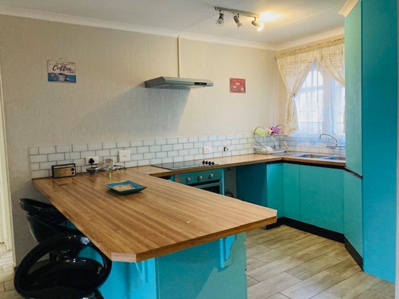 A functional kitchen featuring vibrant blue cabinetry, wood-look laminate countertops, a subway tile backsplash, and integrated cooking appliances.