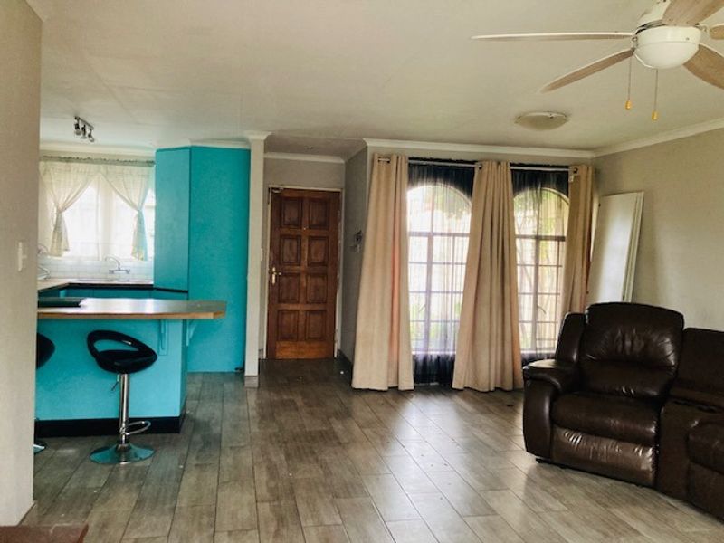 Open plan living and kitchen area featuring tiled flooring, a breakfast bar, ceiling fan, and arched windows providing natural light.
