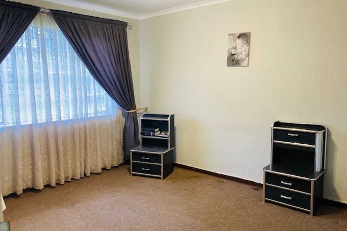 A bedroom featuring carpeted flooring and large window with curtain tracks, offering a neutral space ready for personalization.