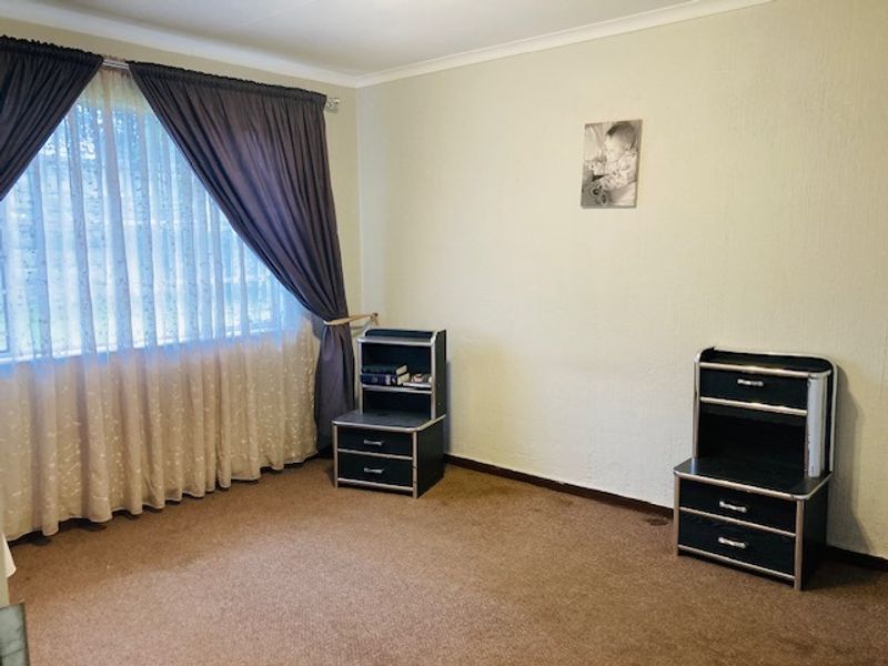A bedroom featuring carpeted flooring and large window with curtain tracks, offering a neutral space ready for personalization.
