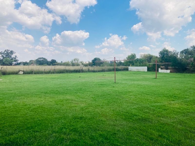 A spacious, open grass garden area featuring rotary clotheslines and perimeter fencing, offering a large outdoor space with potential for landscaping.