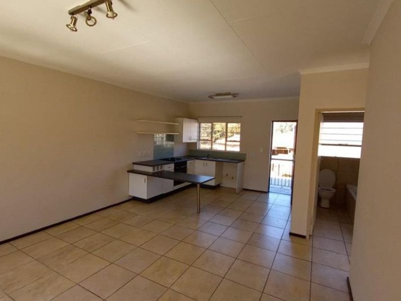 An open-plan living and kitchen area featuring tiled flooring, built-in cabinetry, and direct access to an outdoor balcony.