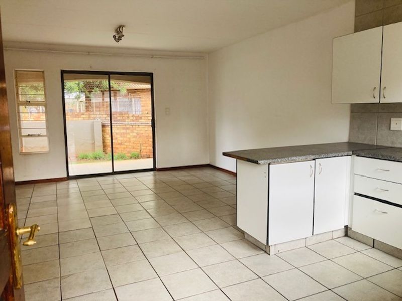 Open-plan living and kitchen area featuring tiled flooring, built-in cabinetry, and a sliding glass door providing access to the exterior.